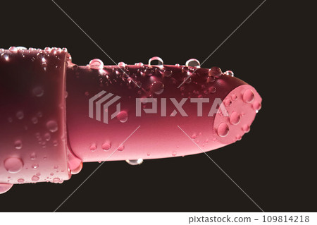 Red lipstick with water drops on a dark background. 109814218