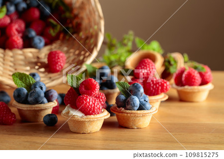 Small tartlets with fresh raspberries and blueberries. 109815275