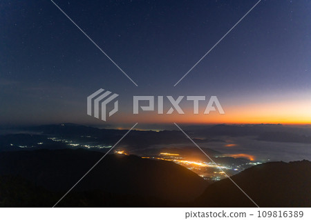Early morning night sky from the top of Doi Luang Chiang Dao in Chiang Mai, Thailand overlooking a glowing town lights and beautiful dark blue sky with stars and glowing golden sun light at the 109816389