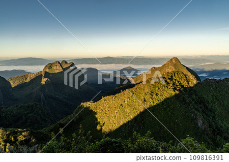 View from the top of Doi Luang Chiang Dao during a morning sunrise with trees and shrubs in the foreground and beautiful mountain ranges in background 109816391