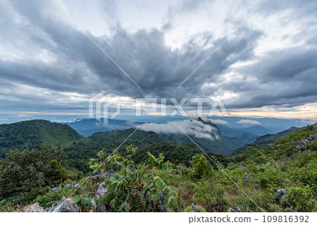 View from the top of Doi Luang Chiang Dao during an evening sunset with trees and shrubs in the foreground and dramatic clouds formation in background View from the top of Doi Luang Chiang Dao during an evening sunset with trees and shrubs in the foreground and dramatic clouds formation in background 109816392