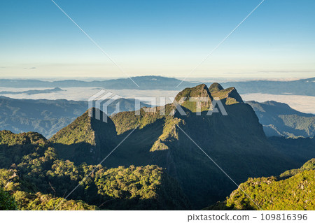 View from the top of Doi Luang Chiang Dao during a morning sunrise with trees and shrubs in the foreground and beautiful mountain ranges in background View from the top of Doi Luang Chiang Dao during a morning sunrise with trees and shrubs in the foreground and beautiful mountain ranges in background 109816396