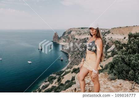 Woman travel sea. Happy tourist taking picture outdoors for memories. Woman traveler looks at the edge of the cliff on the sea bay of mountains, sharing travel adventure journey Woman travel sea. Happy tourist taking picture outdoors for memories. Woman traveler looks at the edge of the cliff on the sea bay of mountains, sharing travel adventure journey 109816777