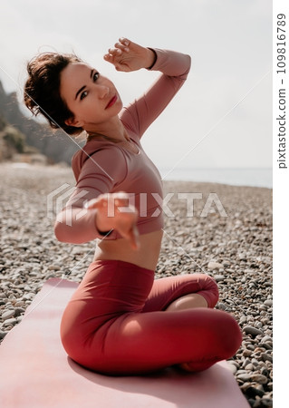 Middle aged well looking woman with black hair, fitness instructor in leggings and tops doing stretching and pilates on yoga mat near the sea. Female fitness yoga routine concept. Healthy lifestyle 109816789