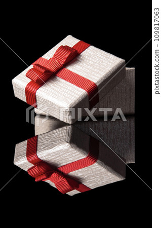 opened gift box with red ribbon isolated on black with reflection 109817063