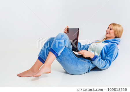 girl in pajamas with a laptop lying on the floor 109818336