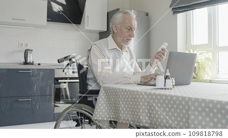 Senior man with disability holding bottle of pills, buying medication online, searching instructions 109818798