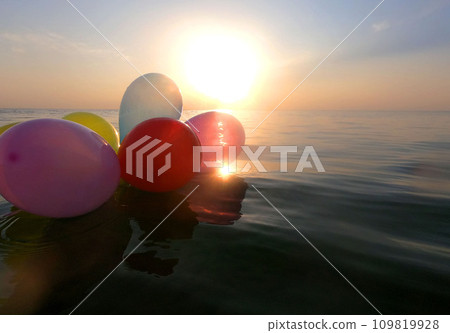 Balloons and sea. Bunch of hot air balloons floats on surface of the sea at dawn and sunset. Multi-colored air balloons on the water of the sea ocean lake pond. Relaxation entertainment romance rest Balloons and sea. Bunch of hot air balloons floats on surface of the sea at dawn and sunset. Multi-colored air balloons on the water of the sea ocean lake pond. Relaxation entertainment romance rest 109819928