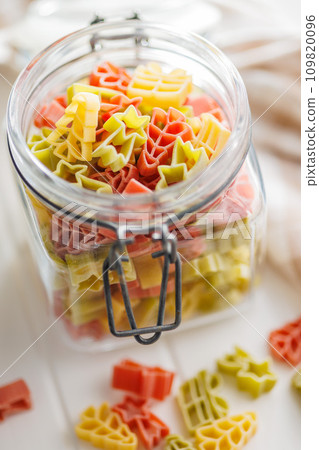 Uncooked raw pasta. Various Christmas shapes. Pasta in jar on white table. Uncooked raw pasta. Various Christmas shapes. Pasta in jar on white table. 109820096