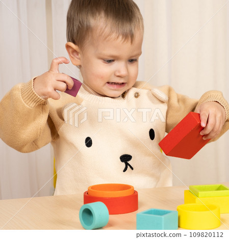 Little boy playing with wooden multicolored Montessori toys. Little boy playing with wooden multicolored Montessori toys. 109820112