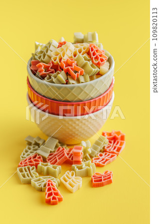 Uncooked raw pasta. Various Christmas shapes.Pasta in bowl on yellow background. 109820113
