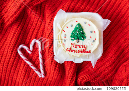 Christmas cupcake with a candy cane heart on a red knitted background. Merry christmas cake inscription. 109820555