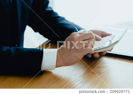 Hand of a man in a suit working on a calculator 109820771