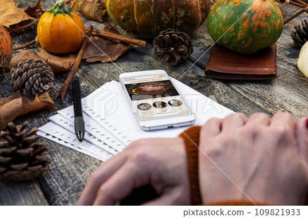 Touchscreen smartphone with online cooking blog on the screen at rustic table in the kitchen. Thanksgiving recipe. Autumn concept Touchscreen smartphone with online cooking blog on the screen at rustic table in the kitchen. Thanksgiving recipe. Autumn concept 109821933
