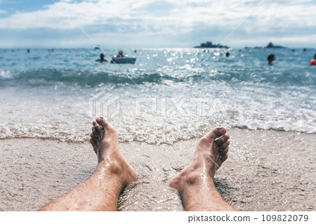 Mans feet on the beach close to water Mans feet on the beach close to water 109822079