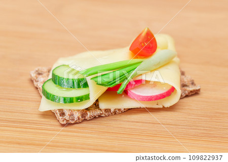 Whole Grain Crispbread with Cheese, Fresh Cucumber, Radish, Tomato and Green Onions Whole Grain Crispbread with Cheese, Fresh Cucumber, Radish, Tomato and Green Onions 109822937
