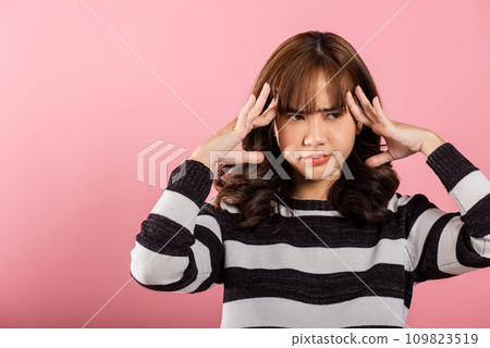 Portrait of beautiful Asian young woman sad tired strain face holding hold head by hands, stress female person unhappy closed eyes problem she headache, studio shot isolated on pink background Portrait of beautiful Asian young woman sad tired strain face holding hold head by hands, stress female person unhappy closed eyes problem she headache, studio shot isolated on pink background 109823519