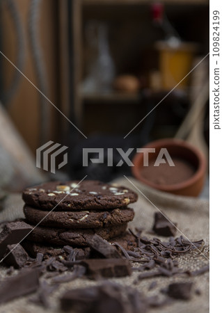 Chocolate cookies with hazelnuts , cocoa and pieces of dark chocolate on the rustic kitchen table Chocolate cookies with hazelnuts , cocoa and pieces of dark chocolate on the rustic kitchen table 109824199