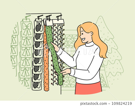 Woman chooses christmas decorations and garlands standing near store counter and new year tree 109824219