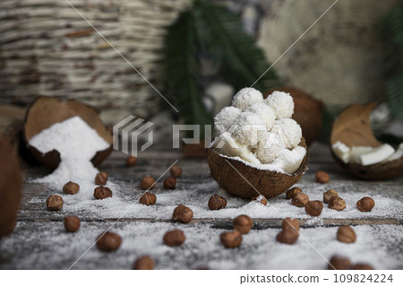 Coconut candy, balls, coconuts and hazelnuts on a rustic wooden surface Coconut candy, balls, coconuts and hazelnuts on a rustic wooden surface 109824224