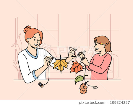 Mom and daughter make garland from tree foliage in autumn to decorate interior of house Mom and daughter make garland from tree foliage in autumn to decorate interior of house 109824237