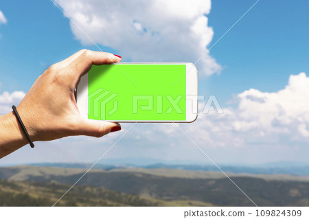 Woman photographing mountain landscape with smartphone. Empty display for copy space Woman photographing mountain landscape with smartphone. Empty display for copy space 109824309