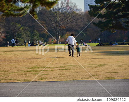 A parent and child playing happily in a park in the city center in autumn 109824512