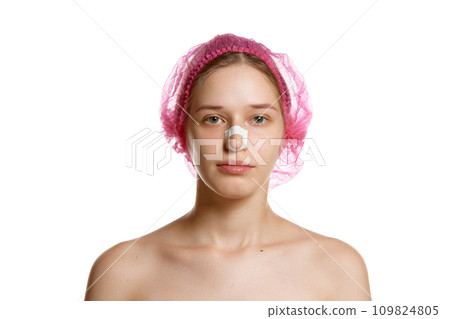 Portrait of attractive woman in pink cap with plasters on nose after rhinoplasty against white studio background. 109824805