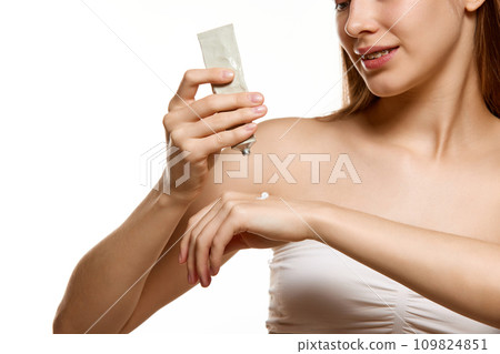 Cropped portrait of female model with naked shoulders apply hand cream for smooth and moisturized skin. Body care cosmetic treatment. Cropped portrait of female model with naked shoulders apply hand cream for smooth and moisturized skin. Body care cosmetic treatment. 109824851