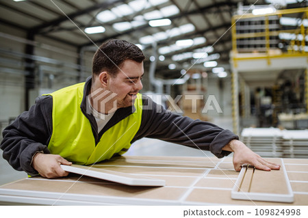 Portrait of young man with Down syndrome working in warehouse. Concept of workers with disabilities, support in workplace. 109824998