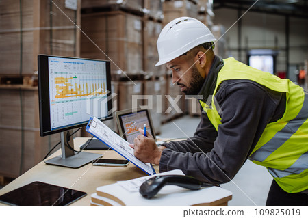 Warehouseman checking delivery, stock in warehouse on computer, pc. Warehouse manager using warehouse management software, app. Warehouseman checking delivery, stock in warehouse on computer, pc. Warehouse manager using warehouse management software, app. 109825019