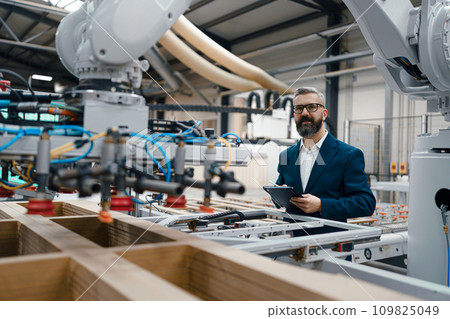 Male engineer in modern industrial factory, checking robotic arm, controling process and manufacturing equipment and machinery. Manufacturing facility with robotics and automation. Male engineer in modern industrial factory, checking robotic arm, controling process and manufacturing equipment and machinery. Manufacturing facility with robotics and automation. 109825049