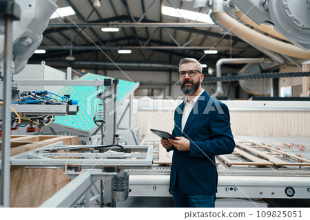 Male engineer in modern industrial factory, checking robotic arm, controling process and manufacturing equipment and machinery. Manufacturing facility with robotics and automation. Male engineer in modern industrial factory, checking robotic arm, controling process and manufacturing equipment and machinery. Manufacturing facility with robotics and automation. 109825051