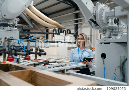 Female engineer in modern industrial factory, checking robotic arm, controling process and manufacturing equipment or machinery. Manufacturing facility with robotics and automation. Female engineer in modern industrial factory, checking robotic arm, controling process and manufacturing equipment or machinery. Manufacturing facility with robotics and automation. 109825053