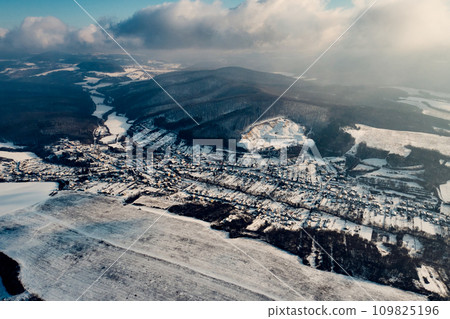 Aerial view of a small village surrounded by a forest during winter. Drone view of snowy landscape, christmas holidays. 109825196