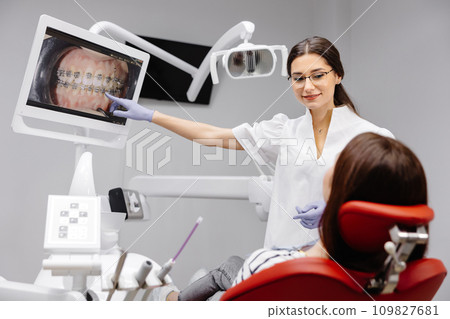 Caucasian dentist woman explaining xray on screen to female patient at clinic Caucasian dentist woman explaining xray on screen to female patient at clinic 109827681