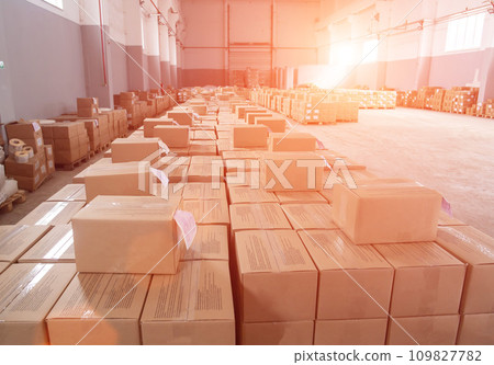 Many cardboard boxes with packaged products in a warehouse against a sunset background. Concept of product packaging and distribution in a warehouse, industry. Copy space for text, stationery Many cardboard boxes with packaged products in a warehouse against a sunset background. Concept of product packaging and distribution in a warehouse, industry. Copy space for text, stationery 109827782