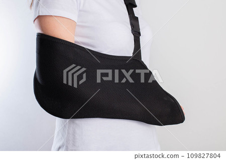 A girl's arm in a black support bandage after a broken arm and sprained shoulder joint. Rehabilitation after injury, close-up A girl's arm in a black support bandage after a broken arm and sprained shoulder joint. Rehabilitation after injury, close-up 109827804