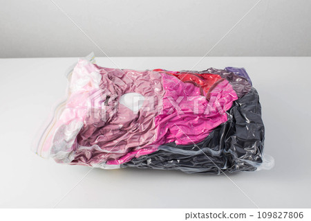 Multi-colored clothes and things packed in vacuum bags for storage on a white background. Modern compact storage technology, close-up 109827806