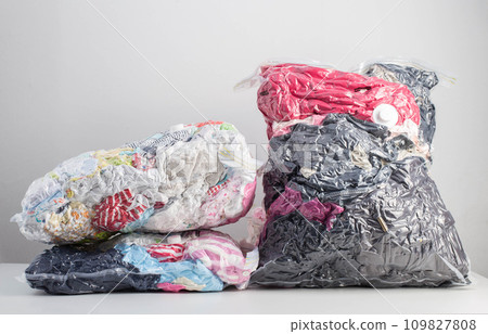 Multi-colored clothes and things packed in vacuum bags for storage on a white background. Modern compact storage technology, close-up 109827808