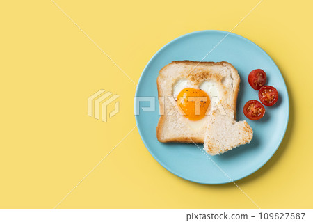 Valentine's Day breakfast with egg with tomatoes, heart shaped and toast bread on yellow background 109827887