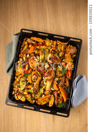 Baked vegetables with ruddy baked chicken on a large metal griddle, copy space Baked vegetables with ruddy baked chicken on a large metal griddle, copy space 109830021