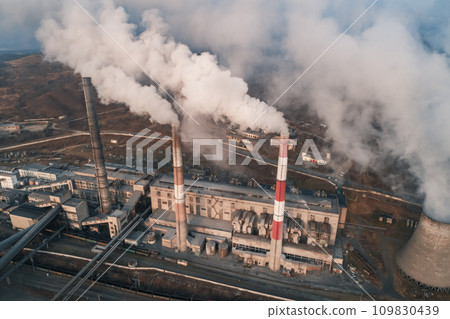 Aerial view of tall chimney pipes with grey smoke from coal power plant. Production of electricity with fossil fuel. Ecology and pollution of nature. 109830439
