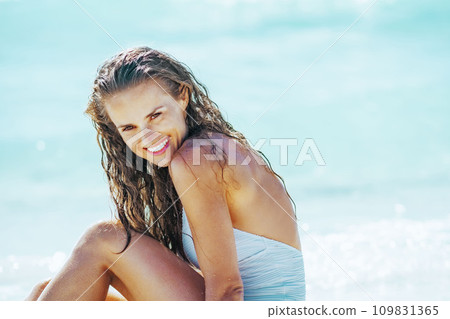Happy young woman sitting at seaside Happy young woman sitting at seaside 109831365