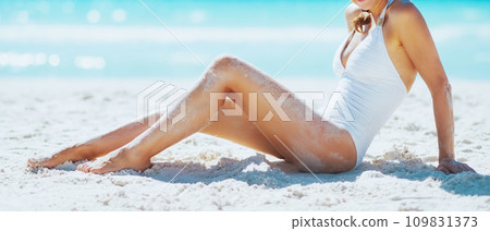 Smiling young woman sitting on beach Smiling young woman sitting on beach 109831373
