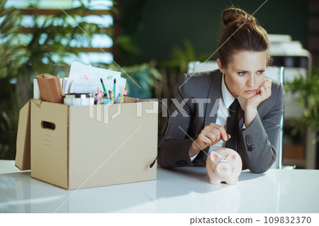 woman employee in green office putting coin into piggy bank woman employee in green office putting coin into piggy bank 109832370