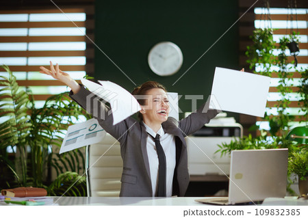smiling woman worker in green office throwing documents 109832385