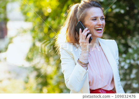 smiling trendy woman in city speaking on smartphone 109832476