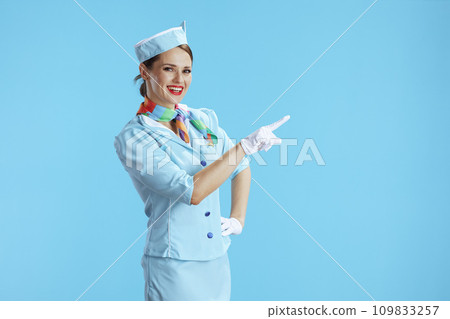 smiling stylish stewardess woman on blue pointing at something 109833257