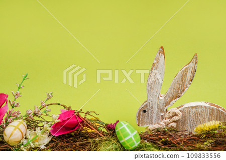 Happy Easter!Wooden Bunny with Decorated Eggs on green background, copy space Happy Easter!Wooden Bunny with Decorated Eggs on green background, copy space 109833556